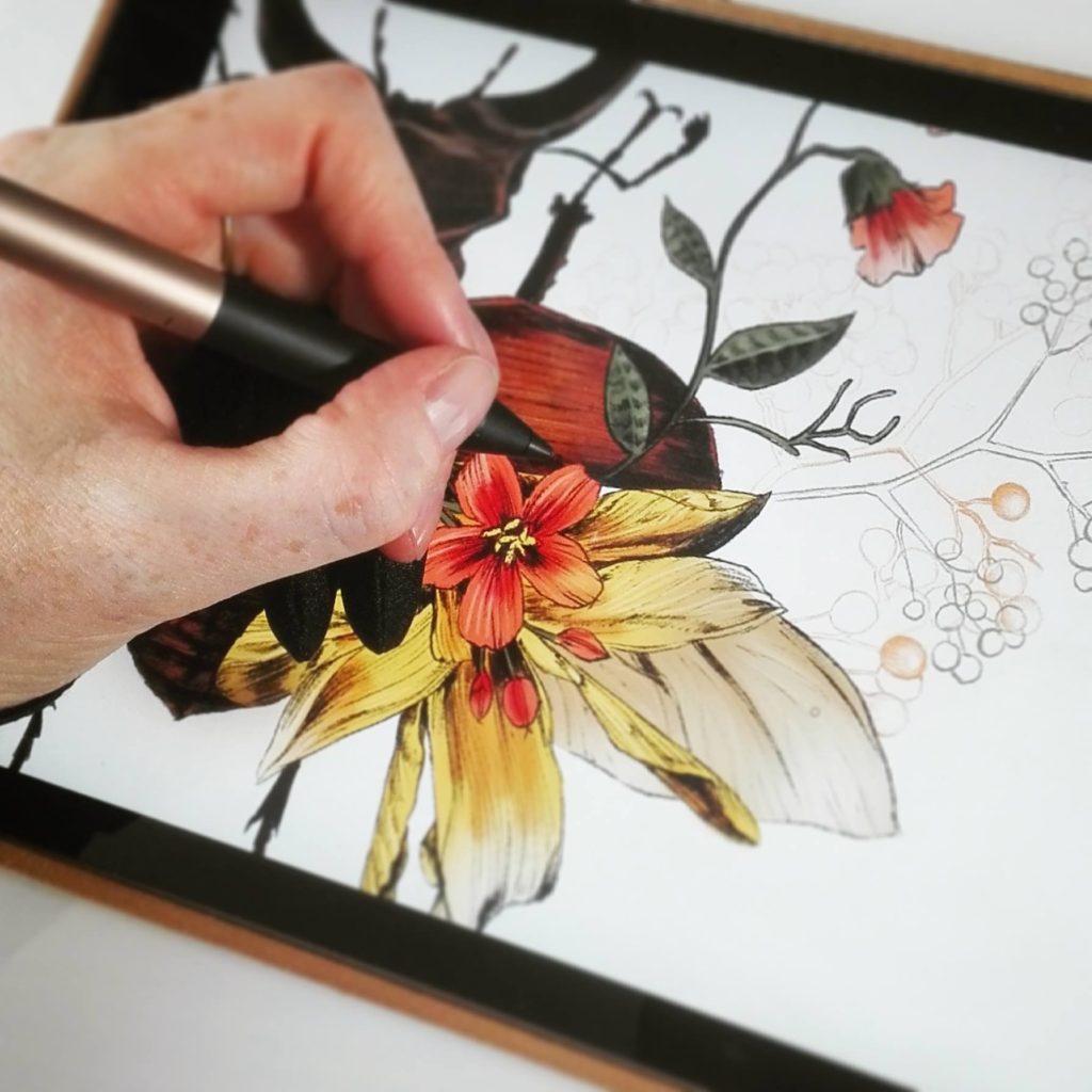 A woman digitally draws flowers on a tablet. 