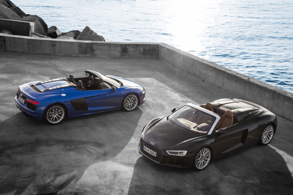 A black and blue luxury car are parked at spots overlooking the ocean. 