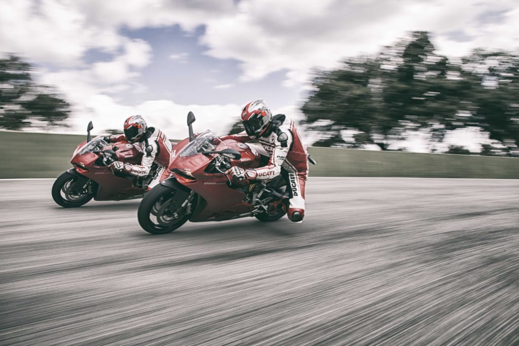 A high speed motorcycle race features two racers in matching white and white suits. 