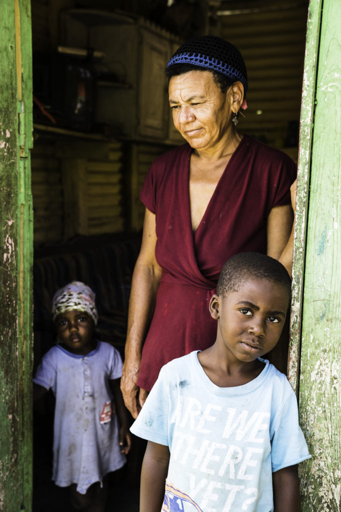 Two children and a woman lean against a doorframe. 