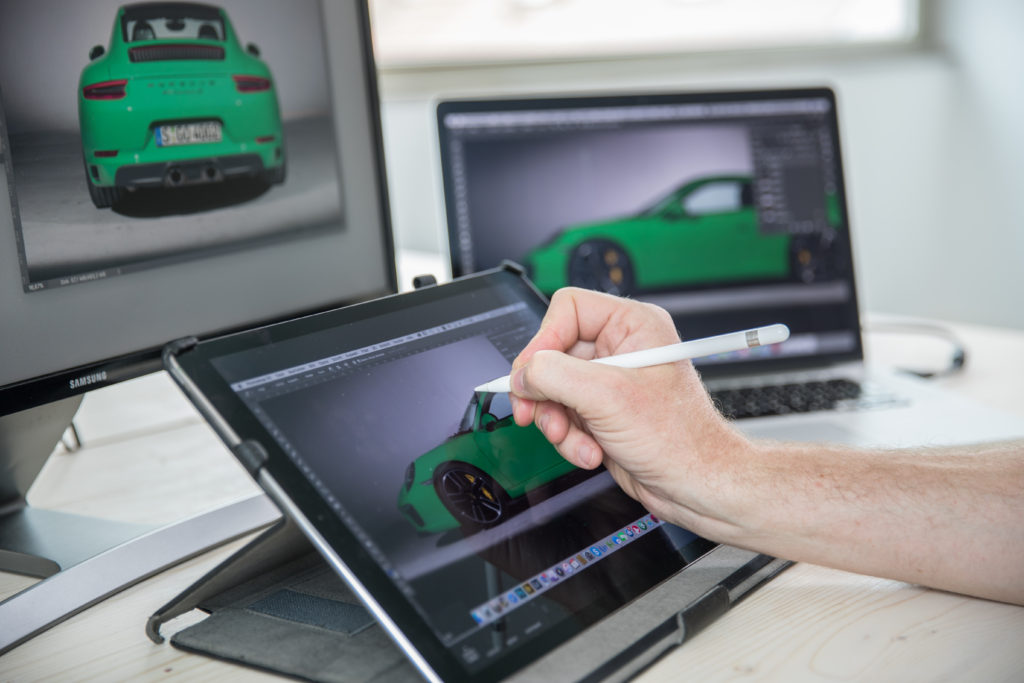 An artist works on touching up a photo of a luxury car. 