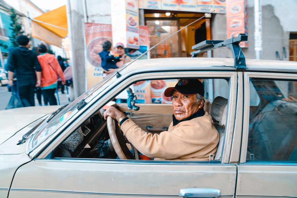A man drives an older brown car