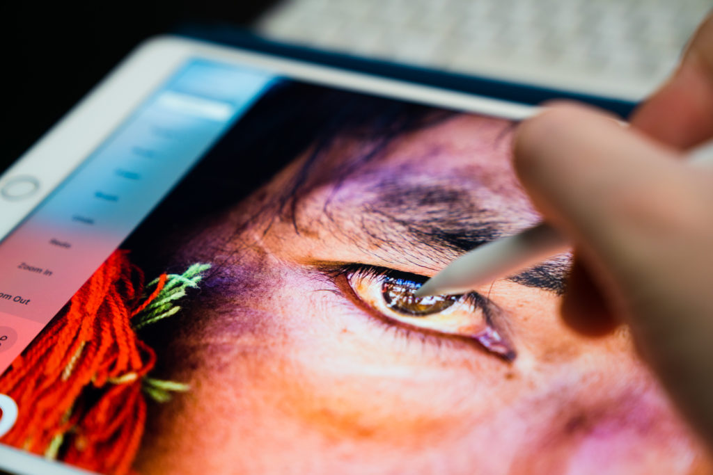 A designer works on touching up a photo of an eye. 