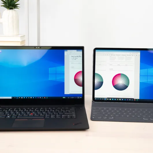 A Windows PC and an iPad sitting side by side at a desk, moving a window between the two devices