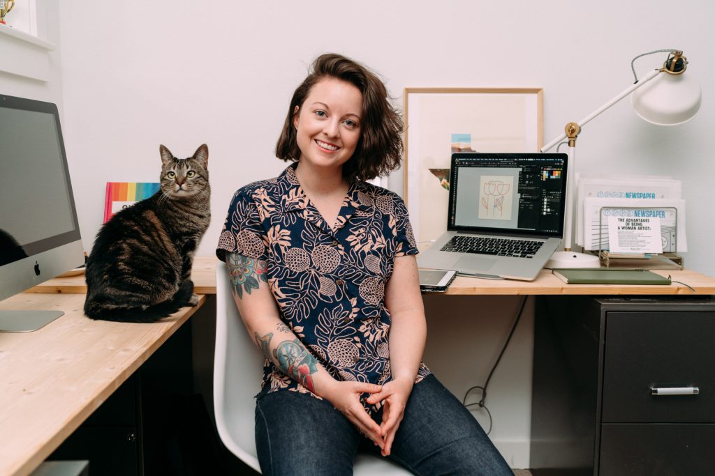 Carra Sykes a designer sits in her office with her cat by her side. 