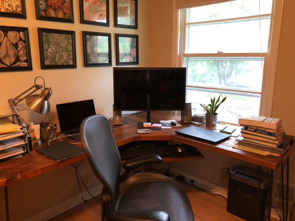 Matt's workstation including a computer, plenty of books, and pictures on the wall. 