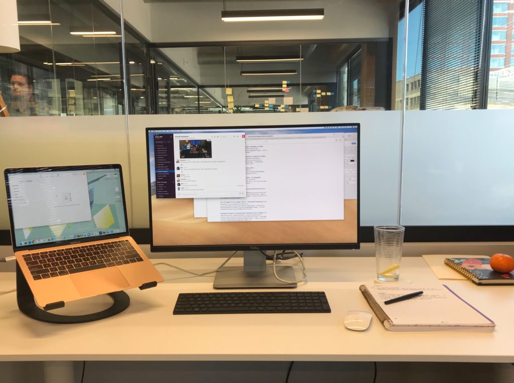 A work station with a computer, monitor, notebook, and wireless mouse and keyboard. 