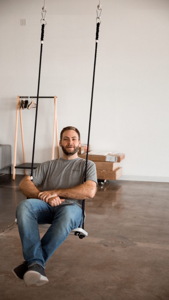 Matt, our cofounder, sits on a swing in the office. 