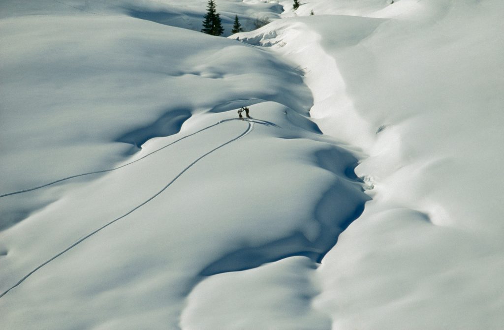 Two snowboarders high-five at the top of fresh snow. 