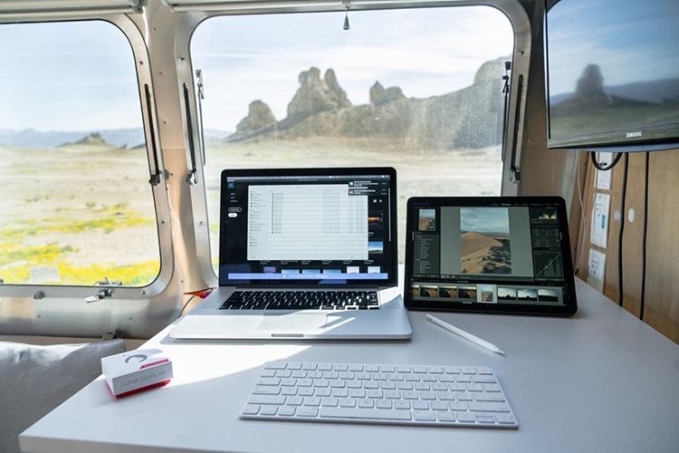 A workstation in an airstream RV with a laptop, tablet, keyboard, and Luna Display. 