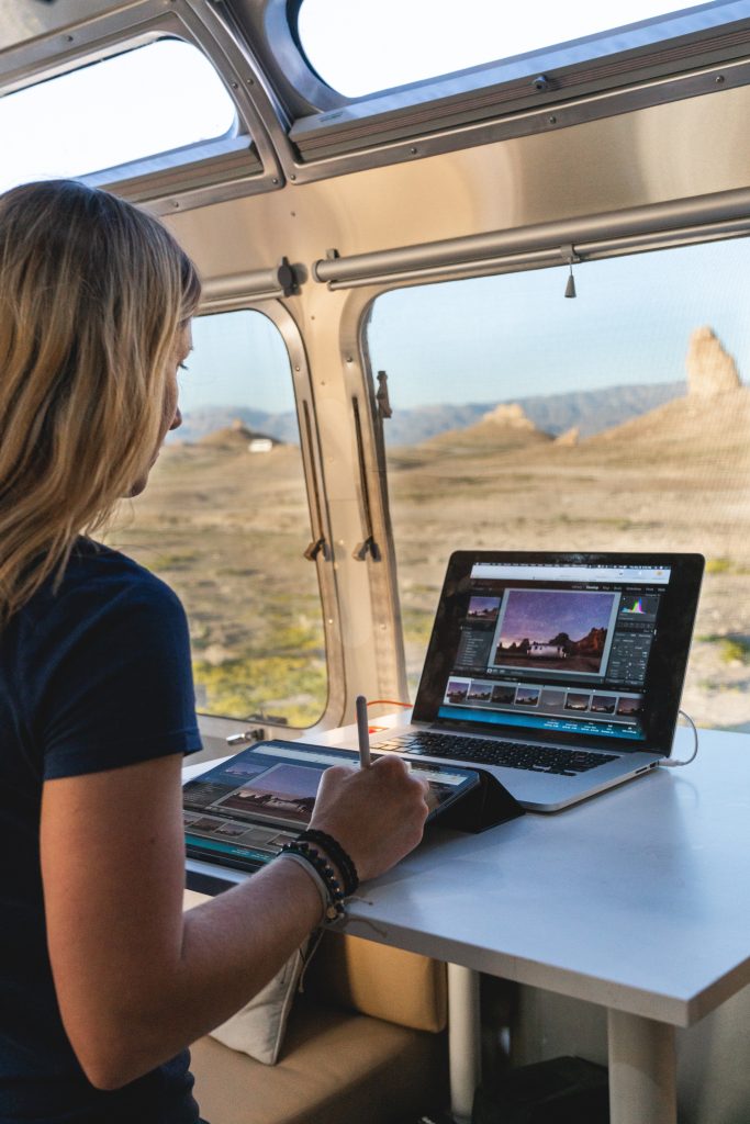Stacey works from her airstream while looking out over a desert. 