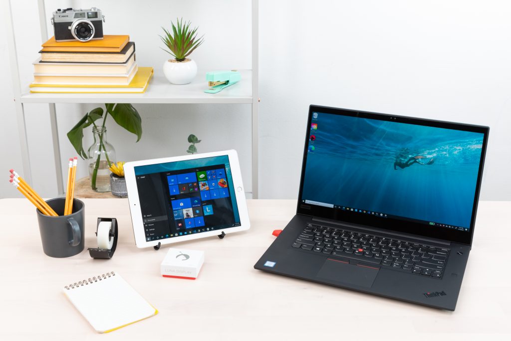 A desk with various supplies, including Luna Display, a tablet, a computer, and more.