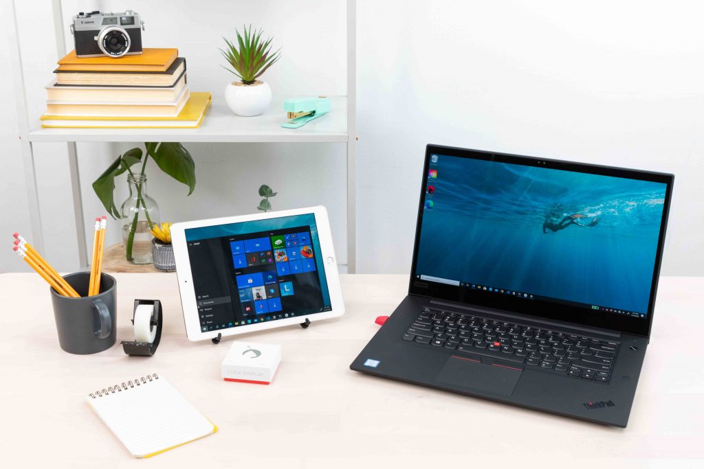 A tablet and laptop on a cluttered desk