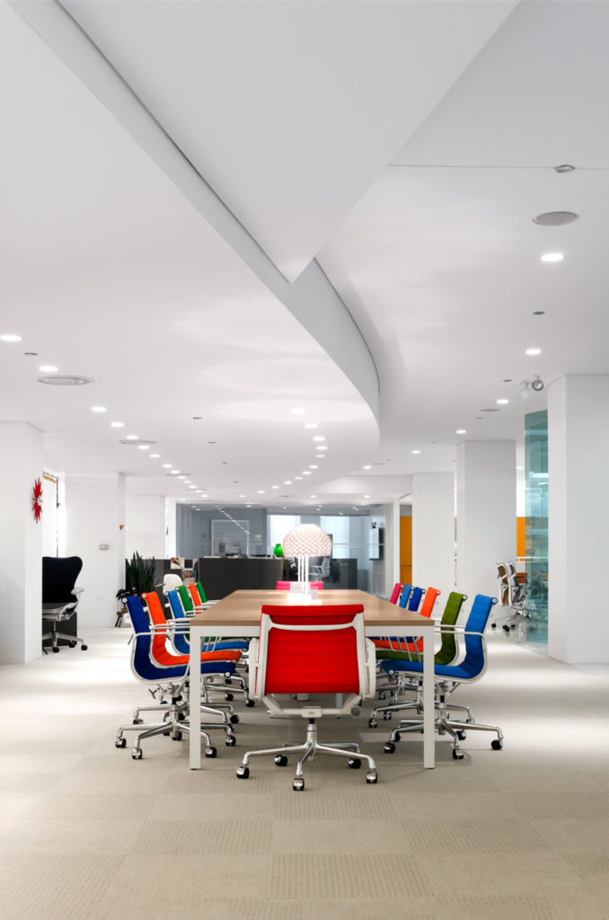 A conference table surrounded by chairs of many different colors. 