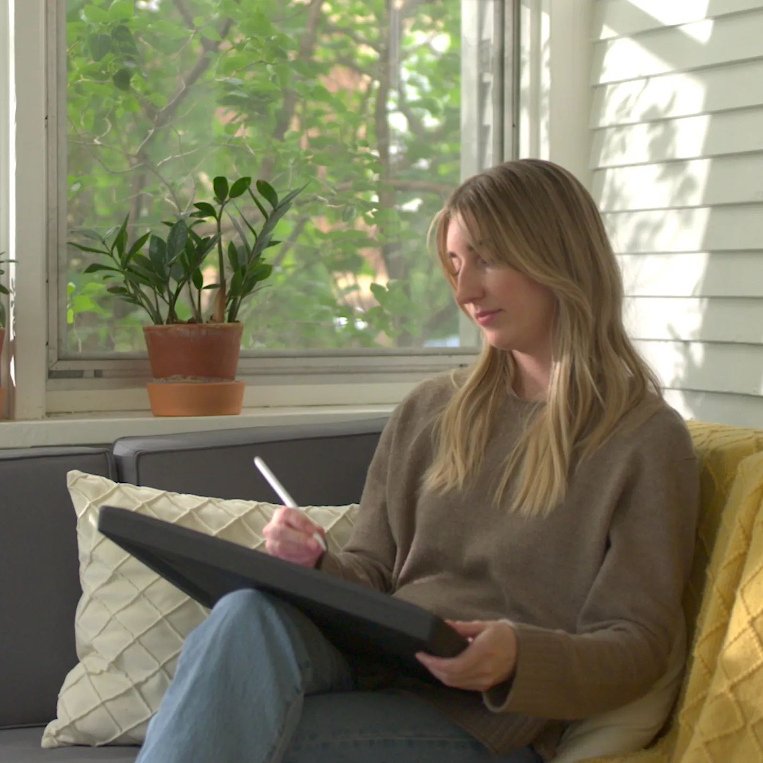 A woman sitting on a patio as she draws on her iPad using Darkboard