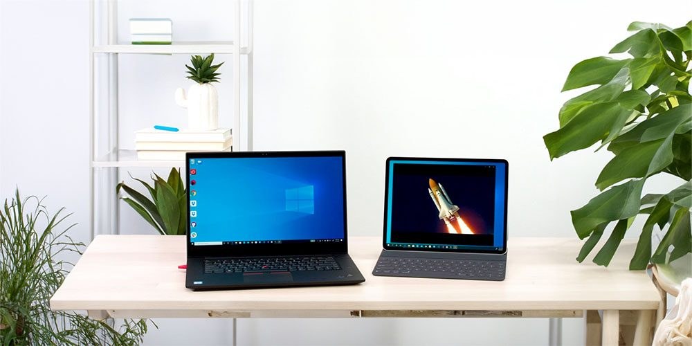 a photo of a pc and an iPad on a desk next to each other with plants around them