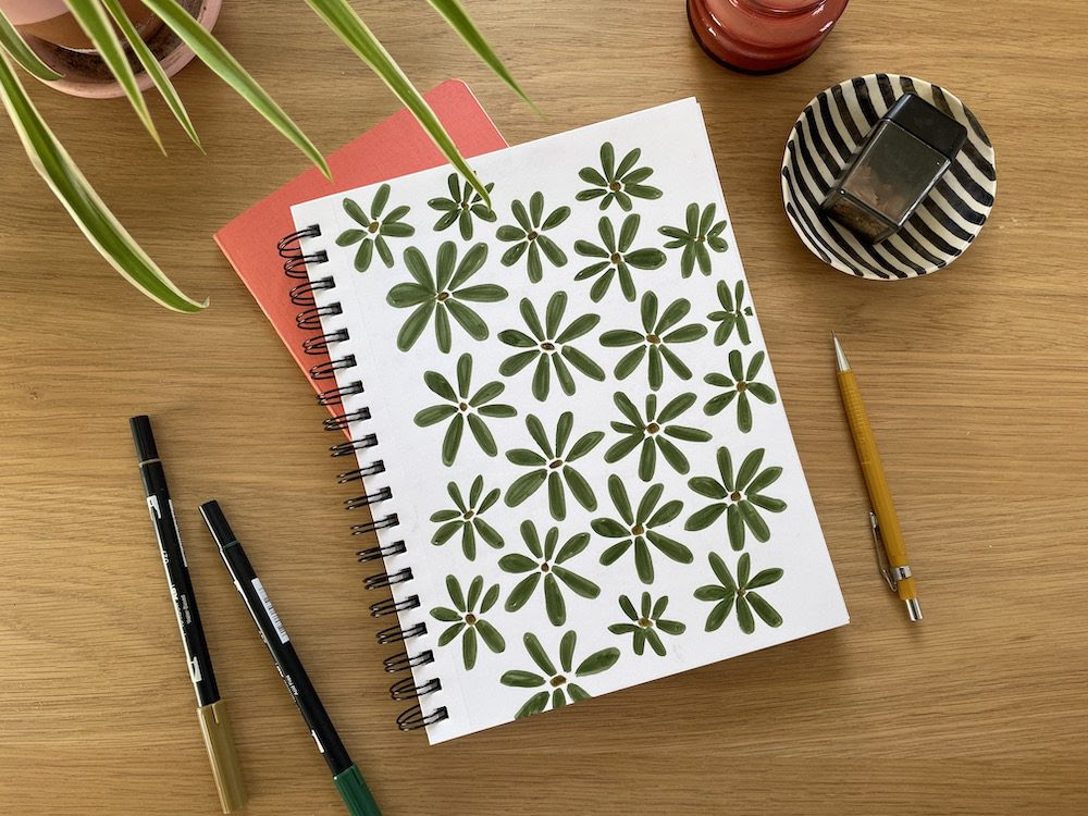 A photo of a notebook on a table with sketches of flowers 