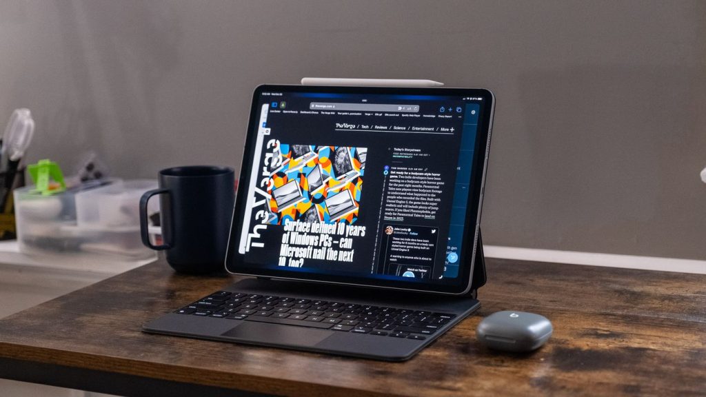 ipad pro on desk with magic keyboard, apple pencil, headphones, and coffee mug 