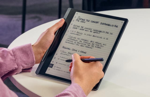 Hands holding a Lenovo Smart paper tablet and stylus, with notes on the screen 