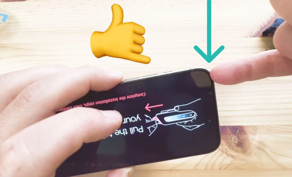 Hands holding an iPhone and gently lifting the corner of a screen protector off of it using their pinky nail.